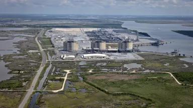 A liquified natural gas plant surrounded by water under hazy skies