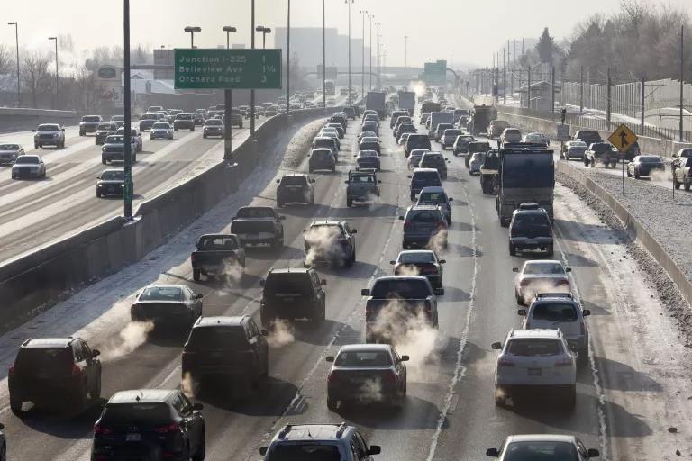Four lanes of cars and trucks sit in traffic on a highway