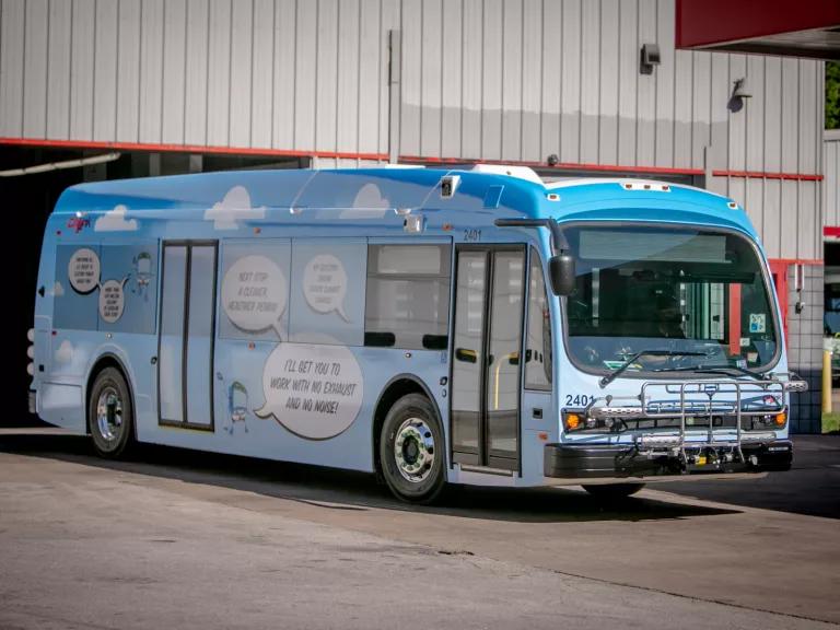A parked electric bus with climate-friendly cartoon bubbles painted on it